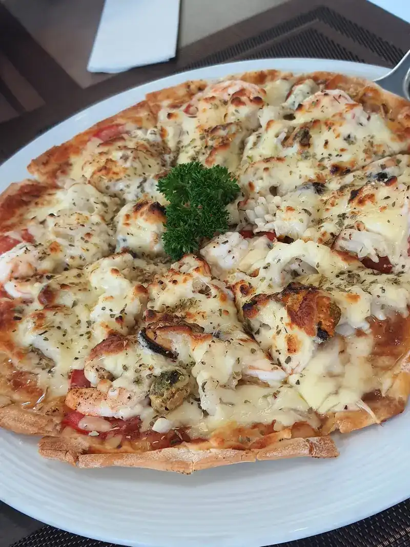 A thin seafood pizza with melted cheese and parsley