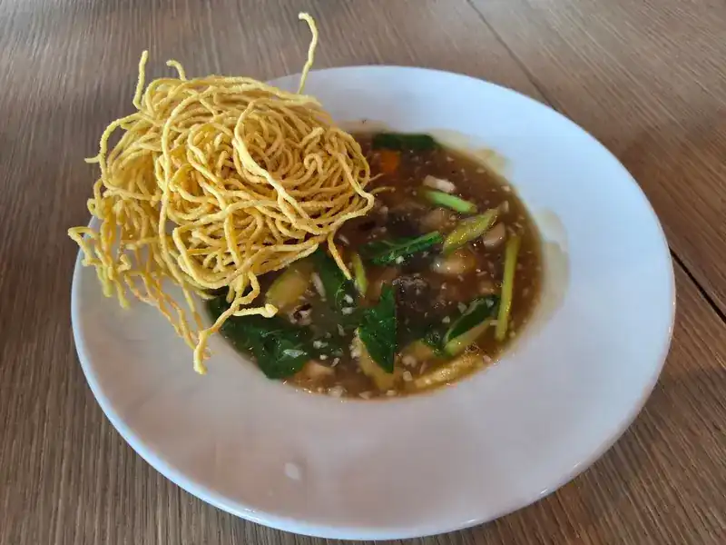 Crispy fried noodles on top of a thick gravy with greens