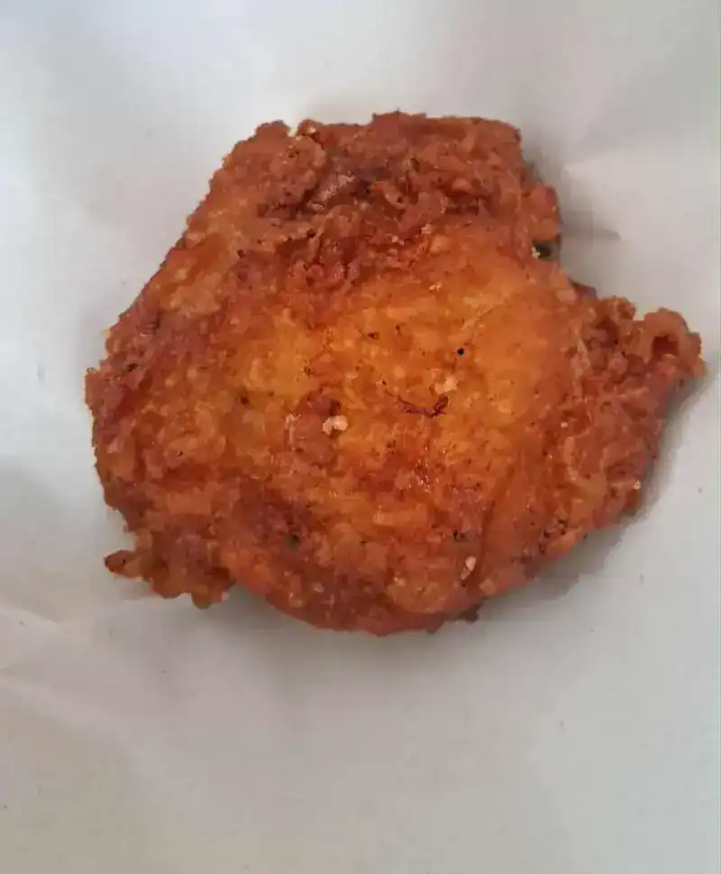 One golden piece of fried chicken on white paper