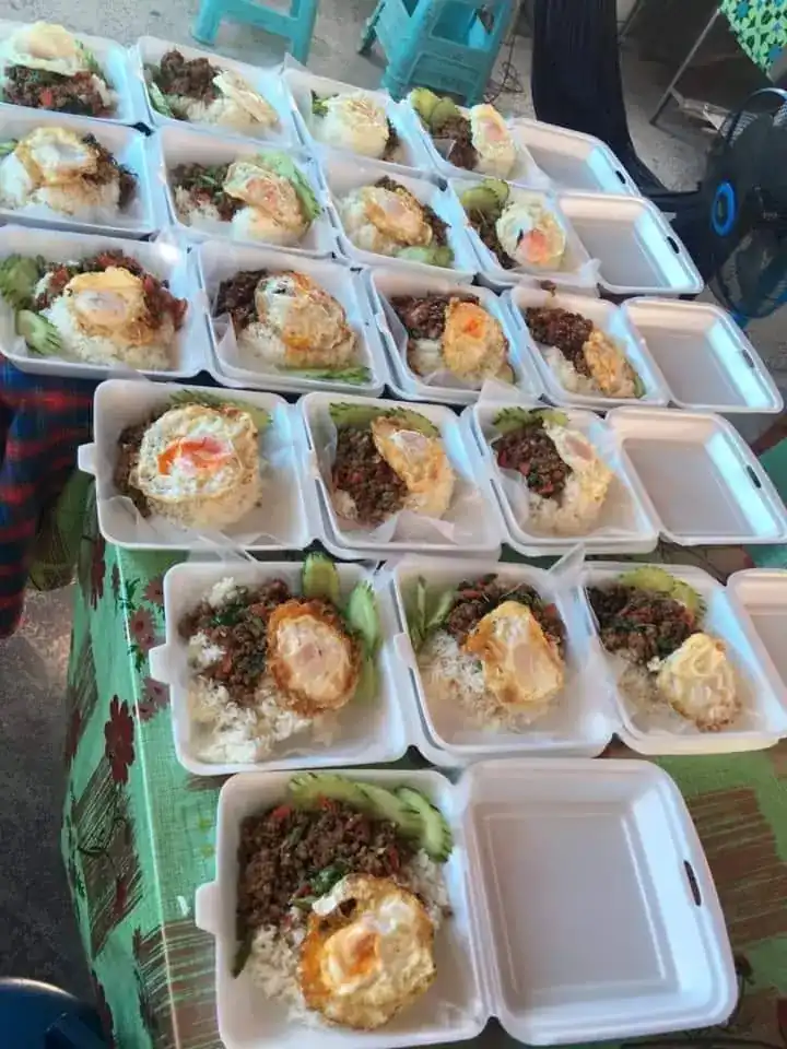 Rows of open takeaway boxes of rice with a stir-fry and a fried egg