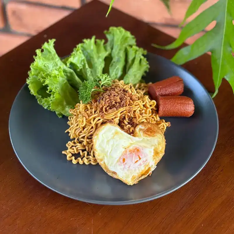 Fried noodles with a fried egg, sausage and lettuce. บะหมี่ผัด ไข่ดาว ไส้กรอก และผักกาด