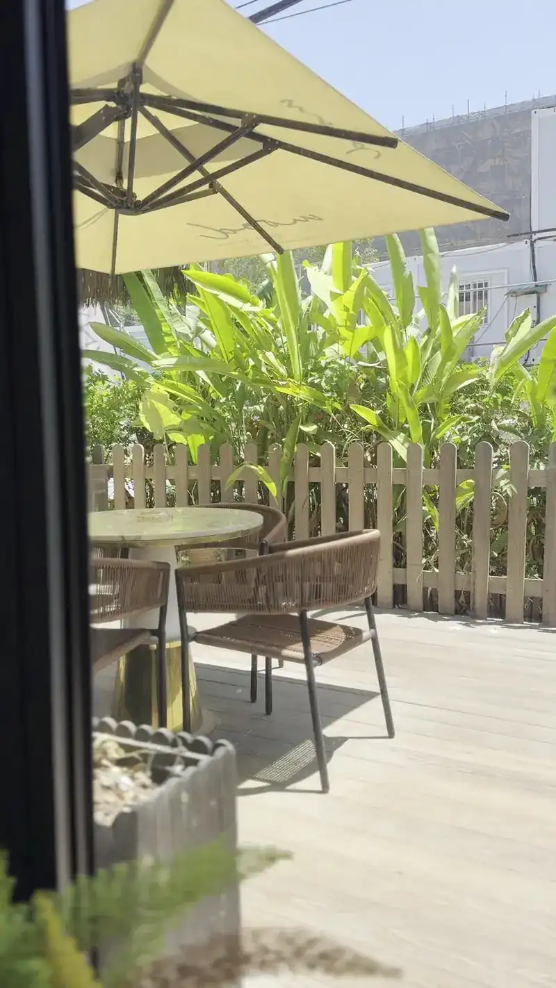 Terrace tables under a yellow umbrella beside the garden fence
