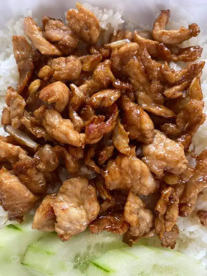 Stir-fried pork pieces over rice with cucumber slices — หมูผัดราดข้าว กับแตงกวาหั่นแว่น