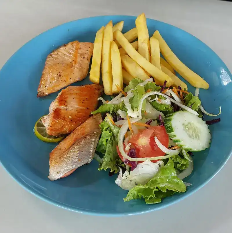 Seared fish fillets with chips and a fresh salad on a blue plate