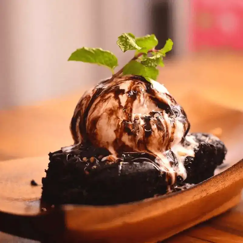 Chocolate brownie with a scoop of ice cream, chocolate sauce and a sprig of mint