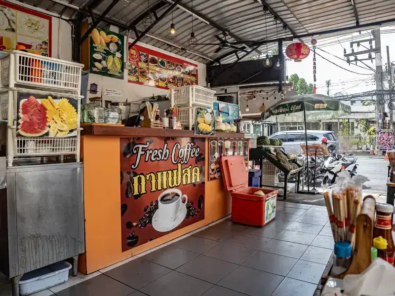 The orange fresh coffee counter at the front, with cut watermelon and pineapple on display