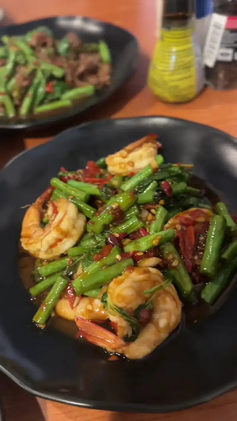 Prawns stir-fried with long beans and red chili in a black bowl