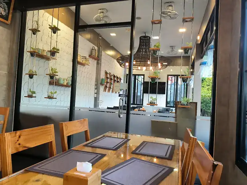 Wooden tables, a glass wall and shelves of small plants