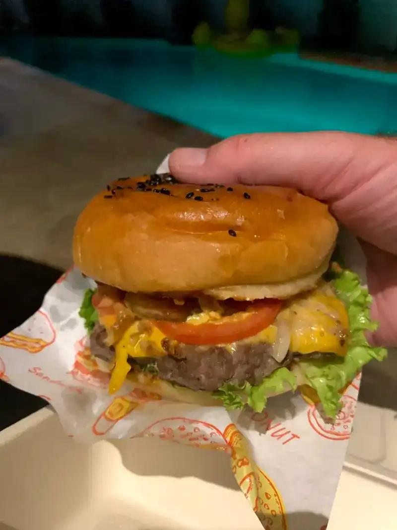 A cheeseburger with tomato and lettuce in a paper wrap