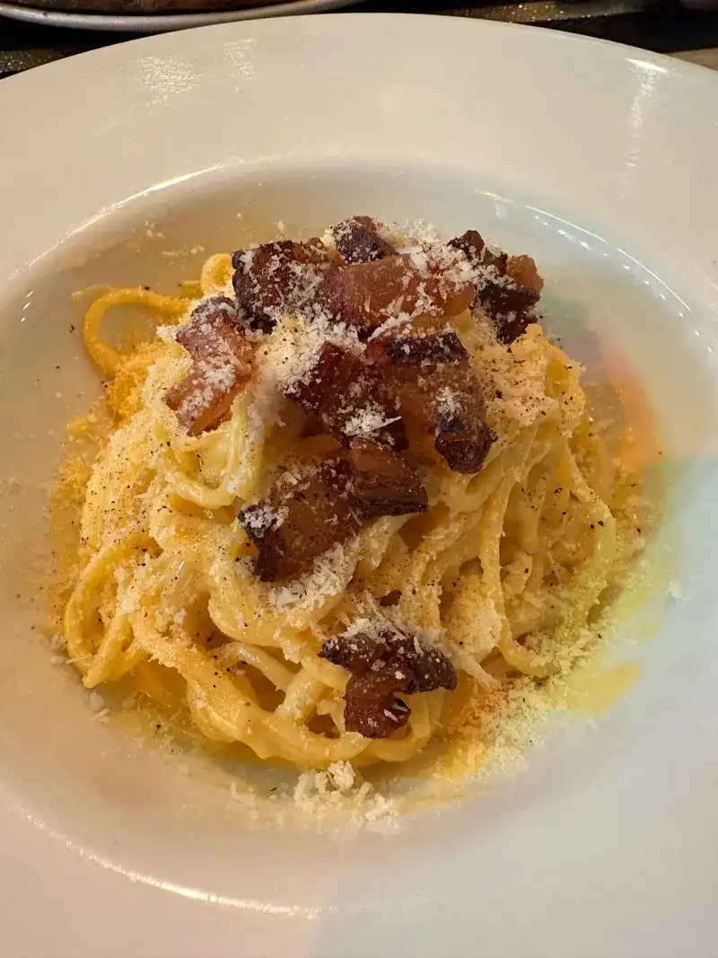 Spaghetti carbonara topped with crisp pork and grated cheese