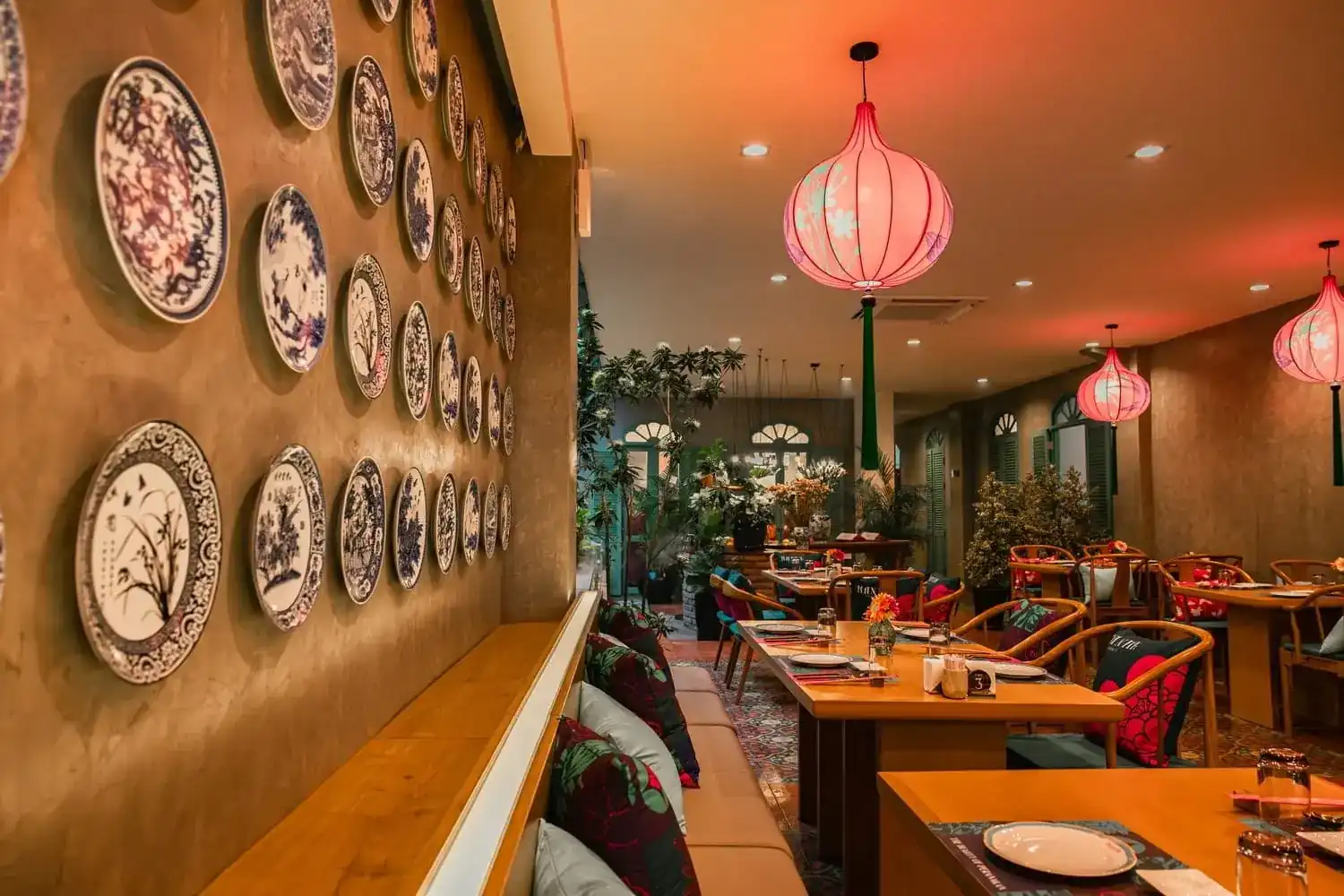 Blue-and-white plates hung along the dining-room wall under pink silk lanterns