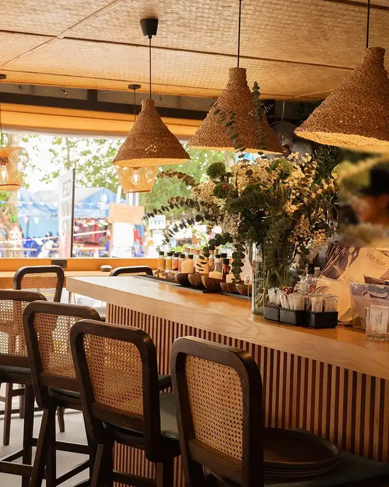 The bar at Vida Nova: rattan lamps over a wooden counter, open to the beachfront