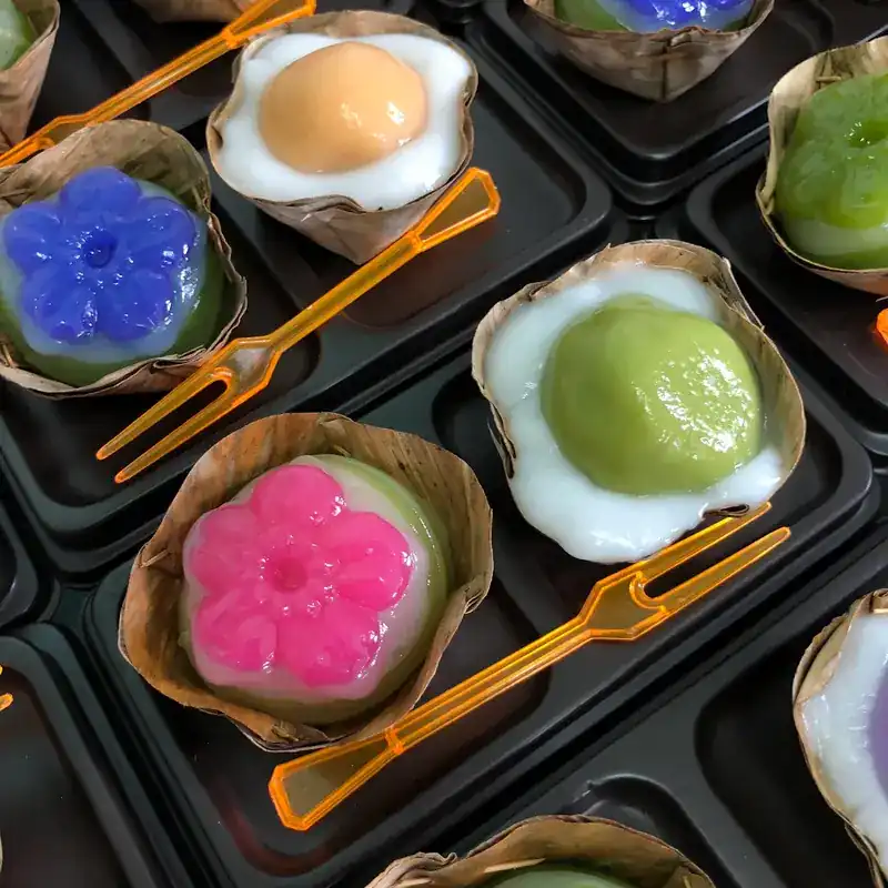 Pink, blue and green sweets in banana-leaf cups with little forks