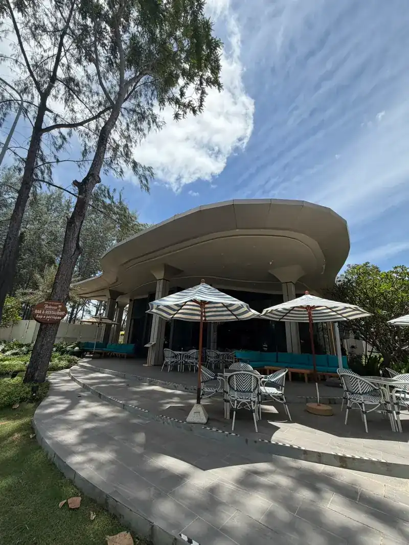 The curved roof and the terrace seen from the garden path under the casuarina trees