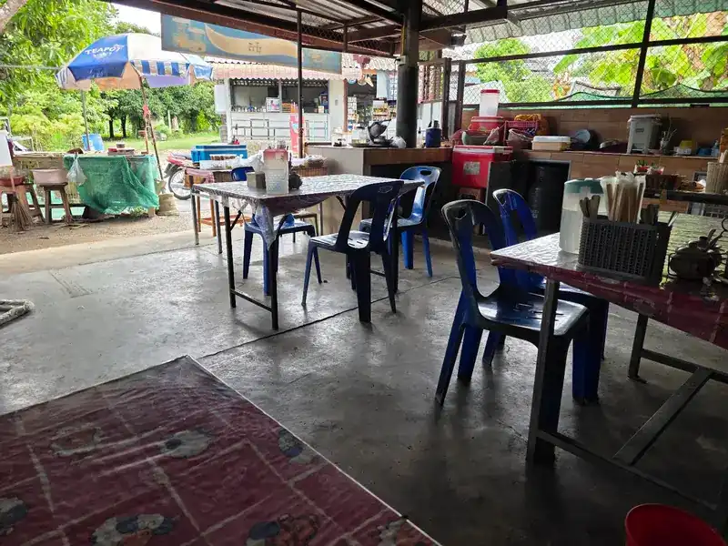 The covered dining area with tables and blue plastic chairs