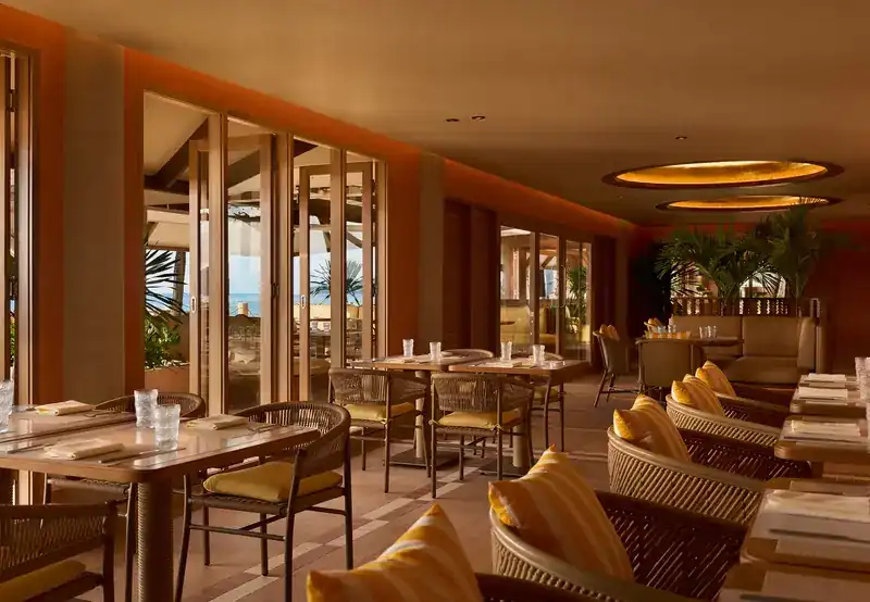 The indoor dining room with rattan chairs and glass doors open to the beach