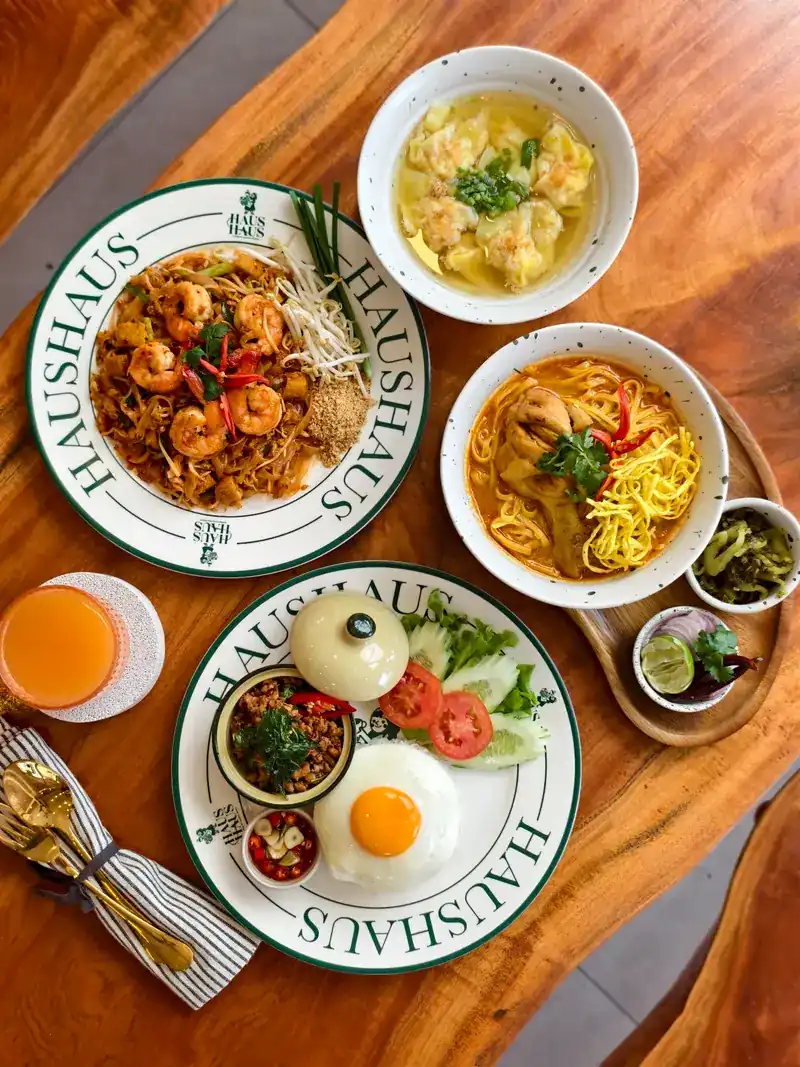 Prawn noodles, curry noodle soup, wonton soup and a rice plate with fried egg, seen from above