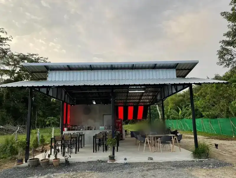 The restaurant from outside: a tin-roofed pavilion with red-and-black awnings among the trees