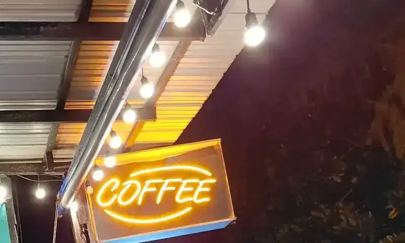 Their orange neon COFFEE sign glowing at night under the roof lights