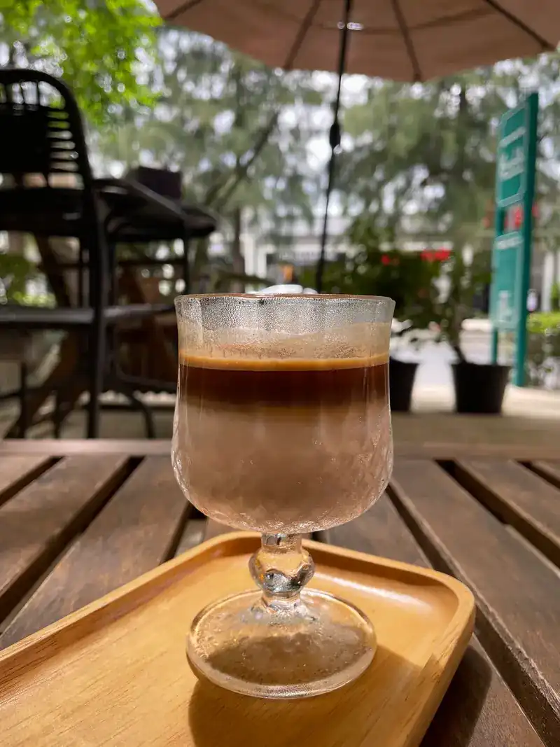 A layered coffee in a stemmed glass on a terrace table