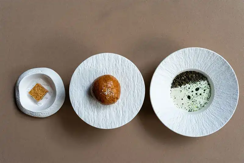 Three small bites in white dishes on a brown table
