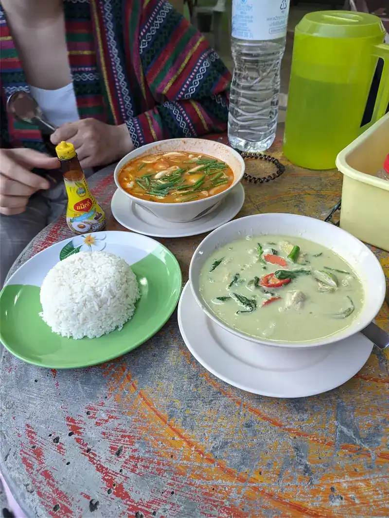 Green curry, a bowl of soup and a plate of rice on the table