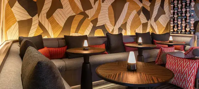 The bar lounge: a patterned wall, low tables with small lamps and red cushions