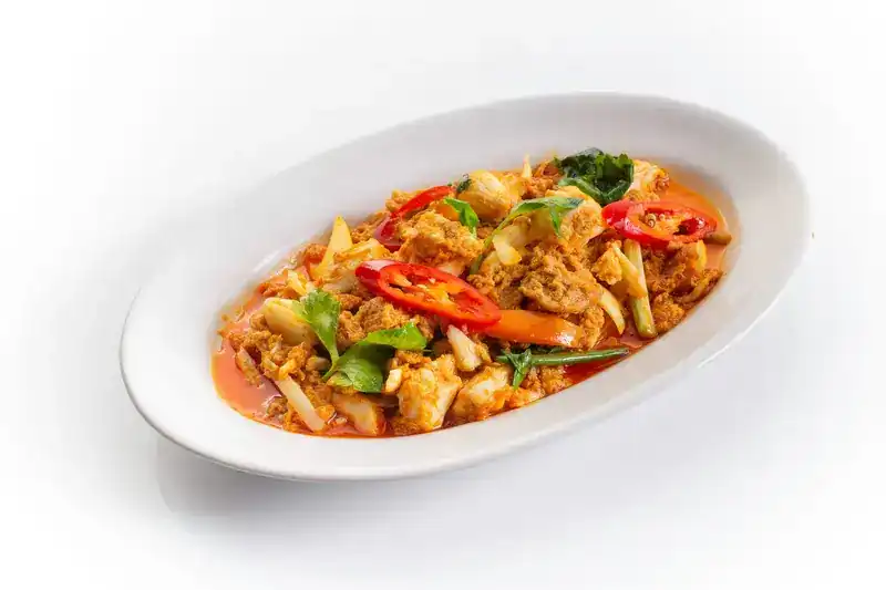 A red curry stir-fry with chillies and basil on an oval plate