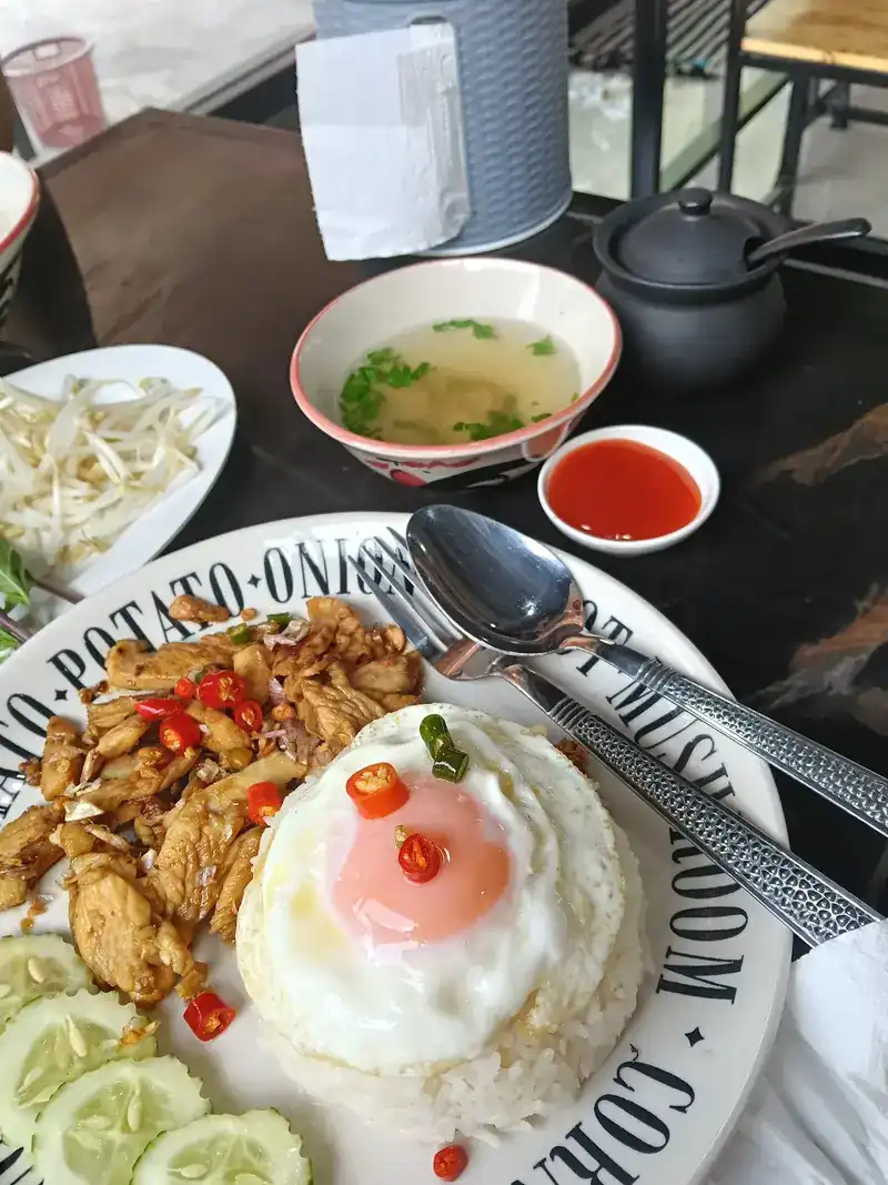 Stir-fry with fresh chilli on rice, a fried egg on top, cucumber on the side