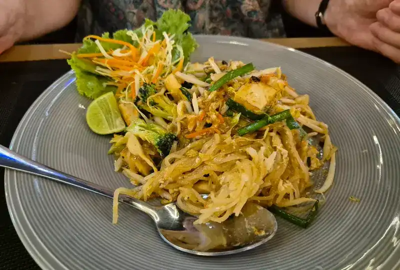 Rice noodles fried with tofu, broccoli and bean sprouts, with lime on the side