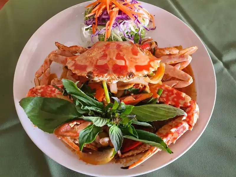 Crab stir-fried with basil leaves in an orange sauce, with shredded salad