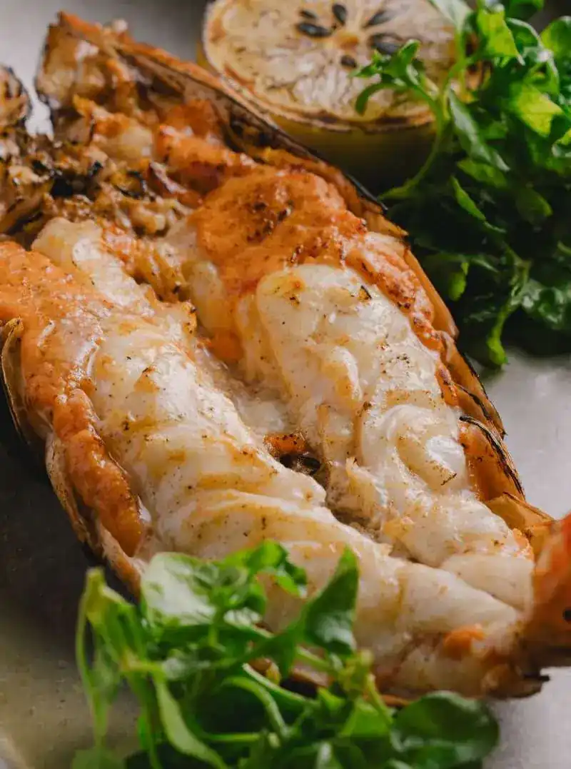 Split grilled tiger prawn with charred lemon and leaves