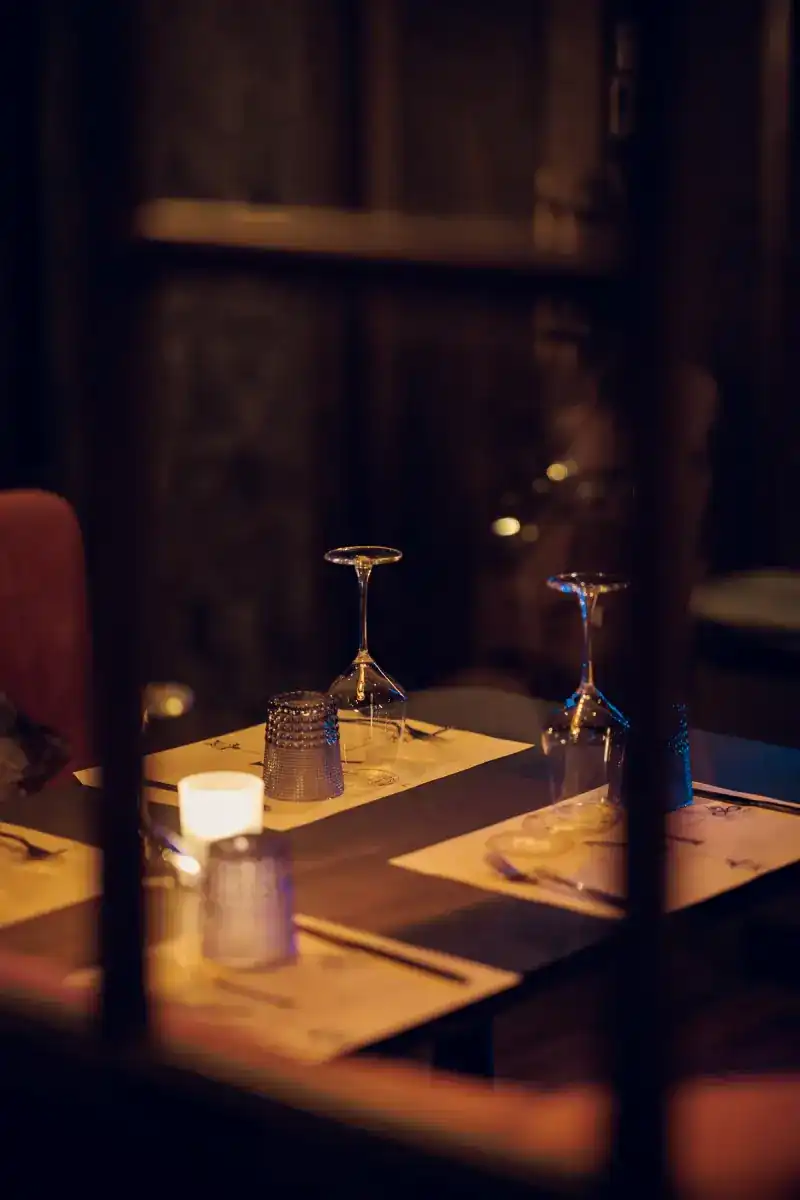 A candlelit table set with wine glasses, seen through the window frames