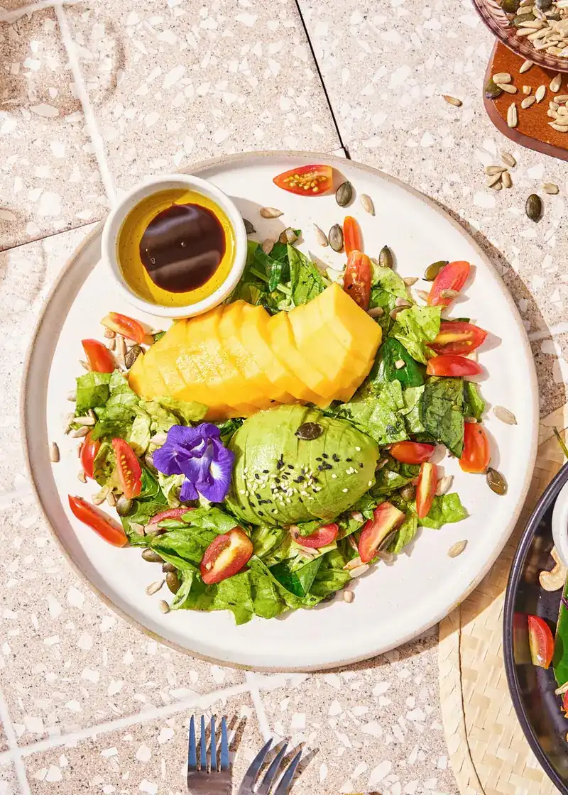 Green salad with mango, avocado and a butterfly pea flower