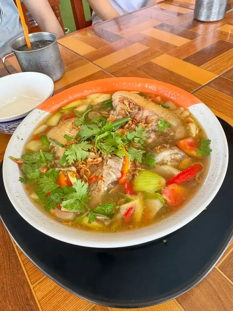 A wide bowl of soup with tomato, chilli and coriander