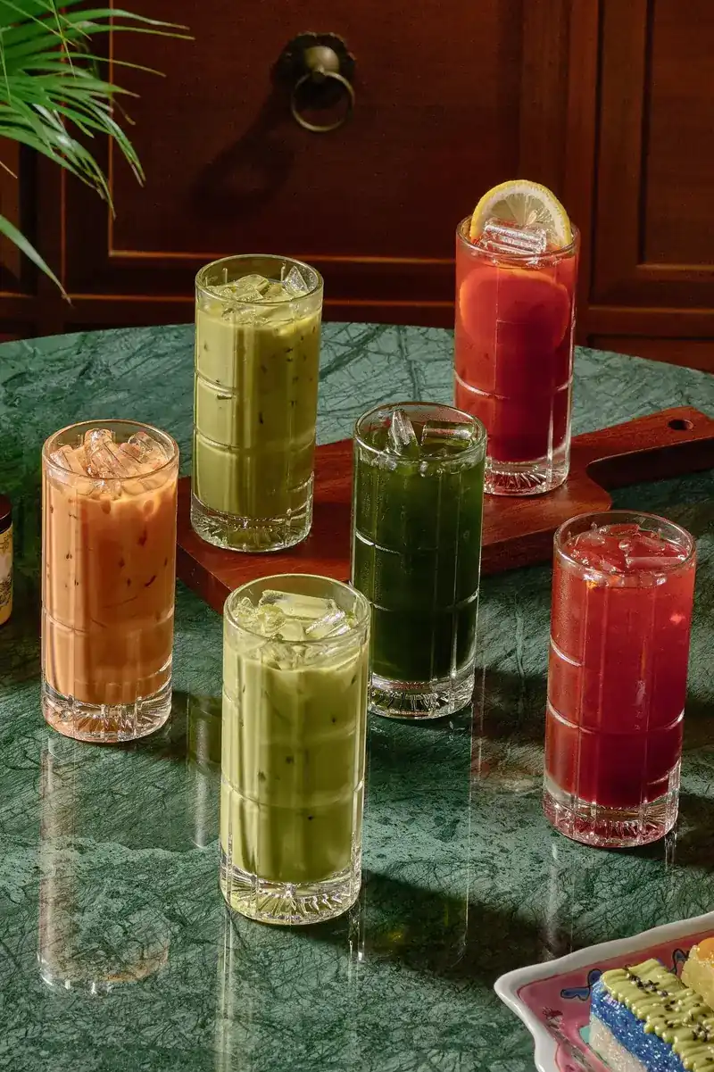 Iced teas and juices in tall glasses on a green marble table