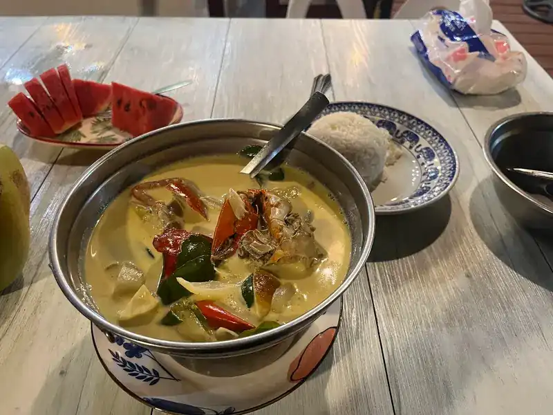 A bowl of coconut curry with rice and watermelon on the side