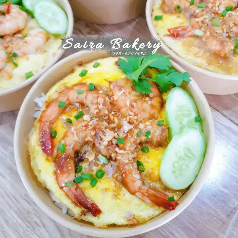 Prawns over a soft omelette on rice, with cucumber and coriander, in a paper bowl