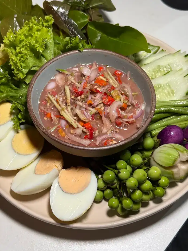 A chilli and shallot dip with boiled eggs, pea eggplants and fresh greens