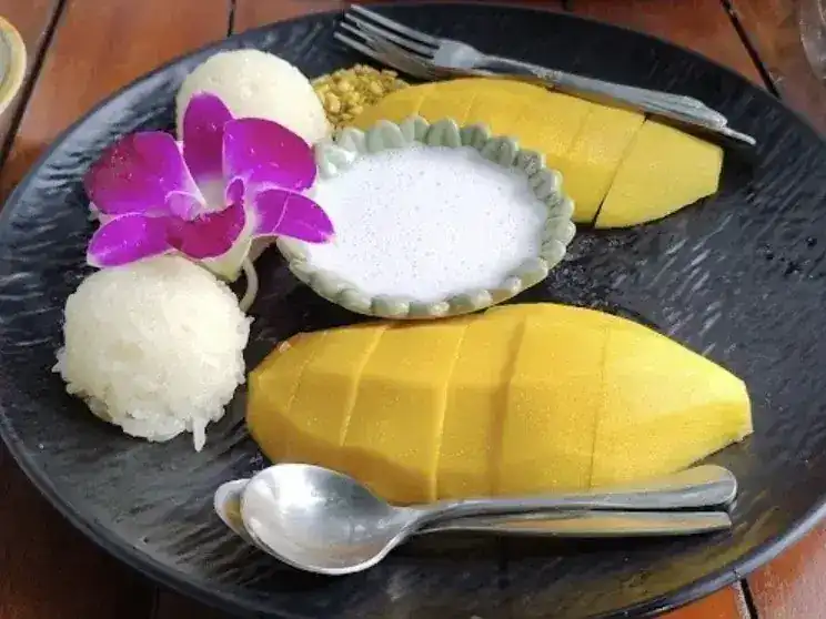 Mango sticky rice with coconut cream and an orchid