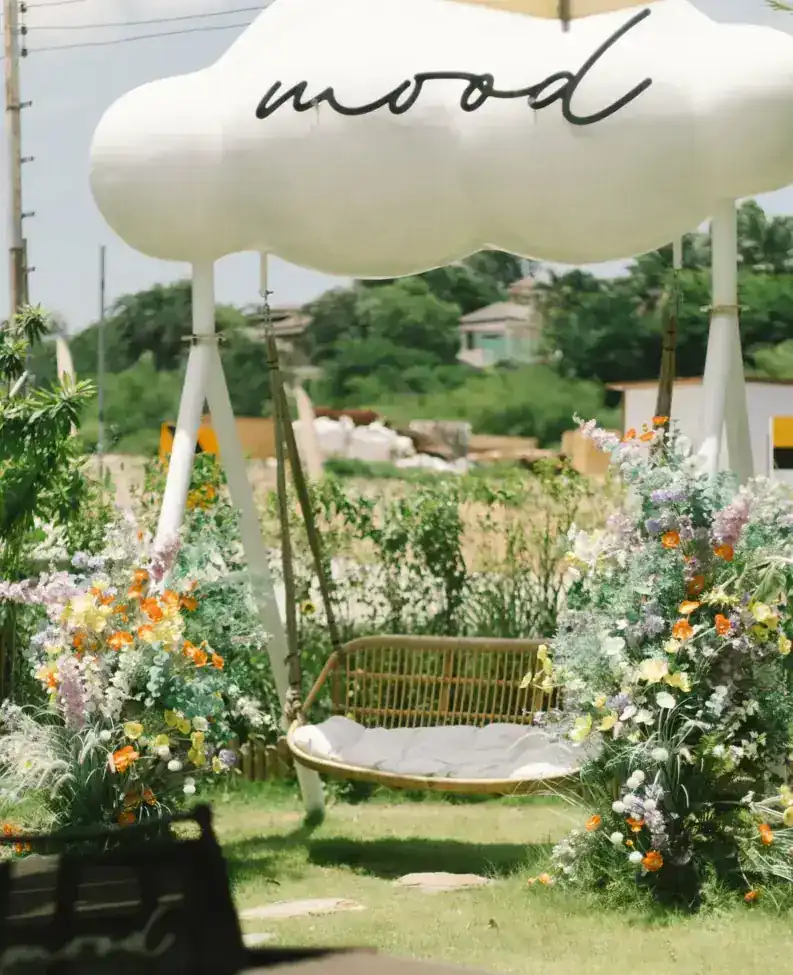 A rattan swing under the white mood cloud, between wild flowers in the garden