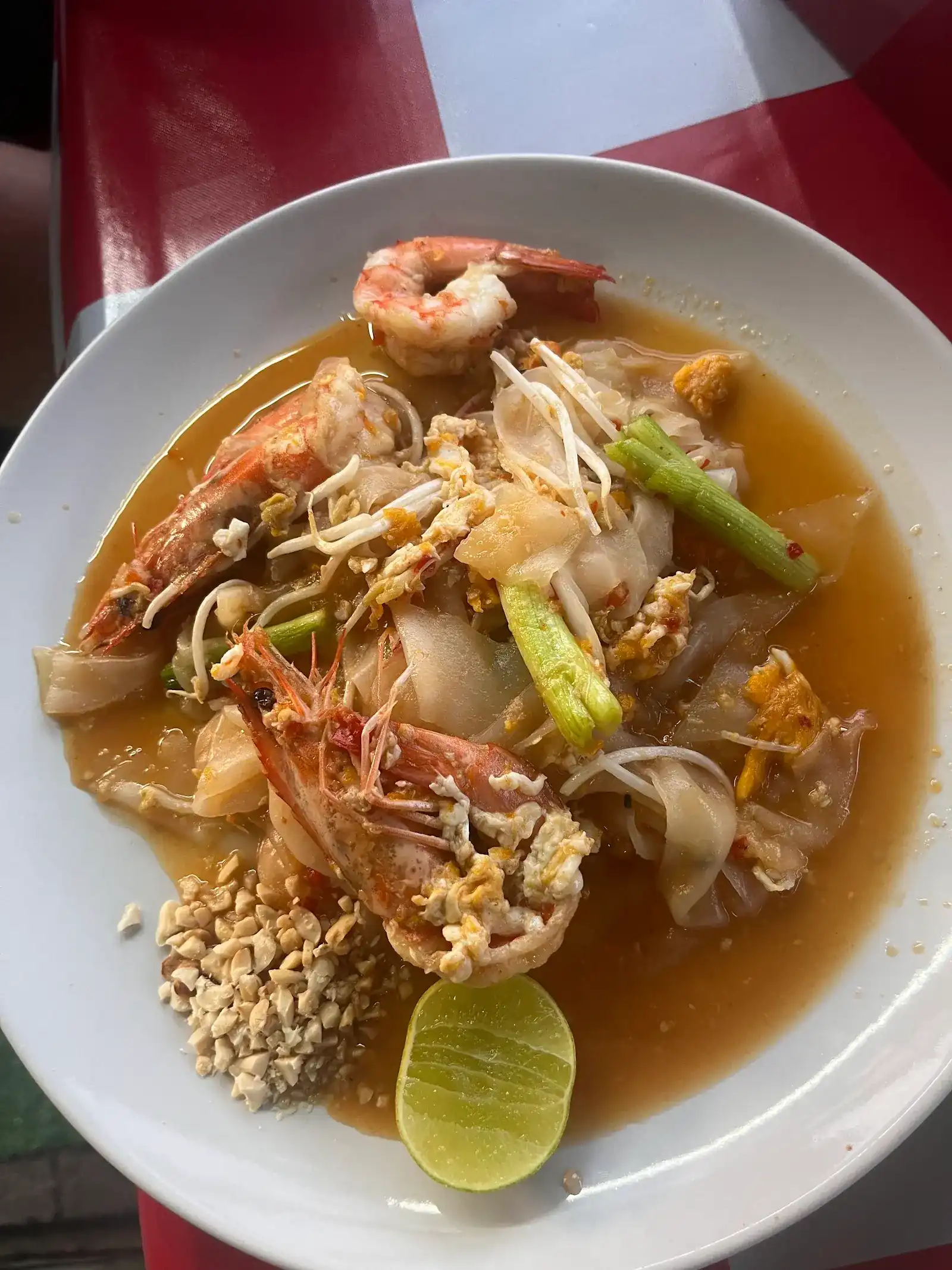 Wide rice noodles fried with big prawns, egg and bean sprouts, with crushed peanuts and lime