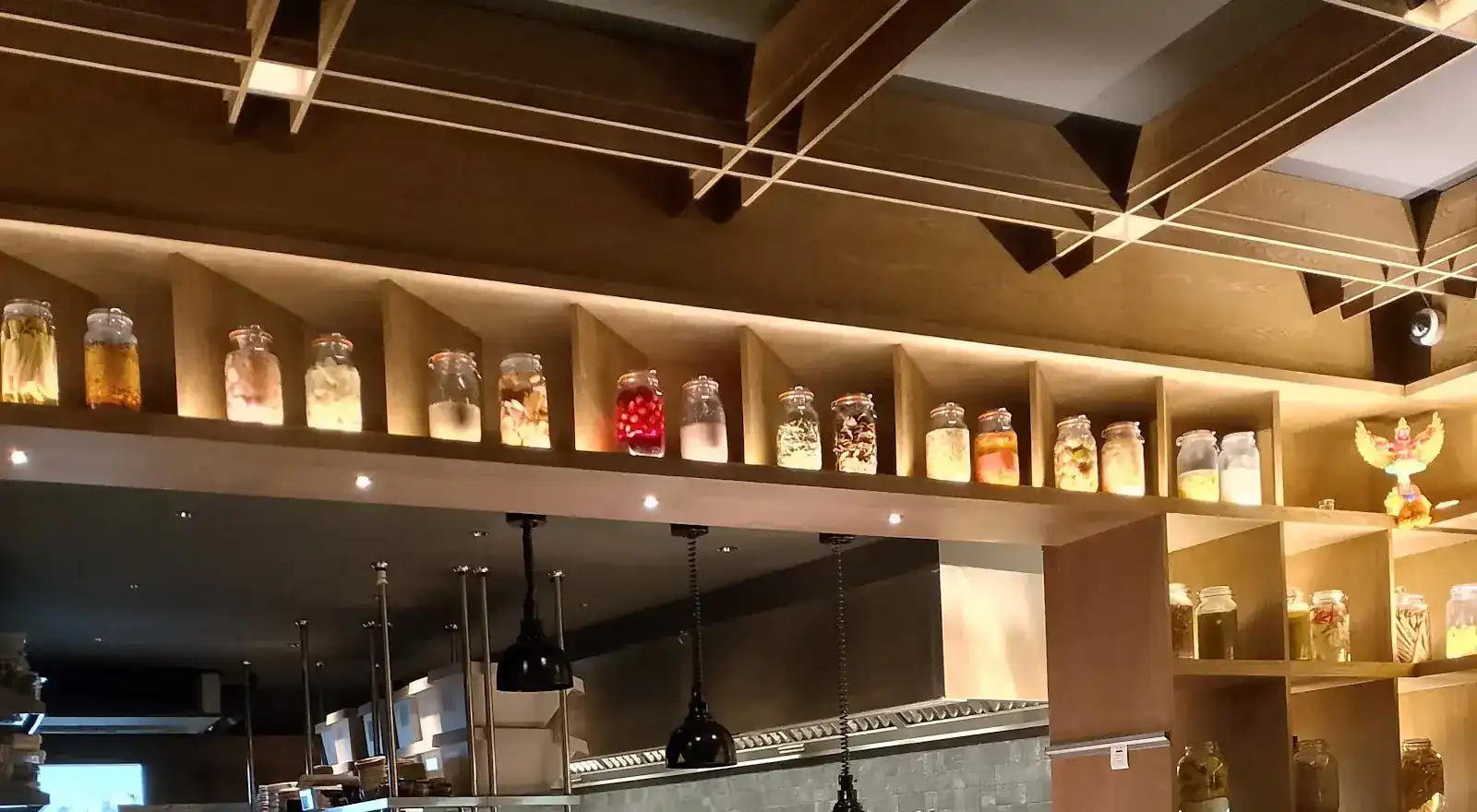 Rows of lit glass jars on wooden shelves above the open kitchen