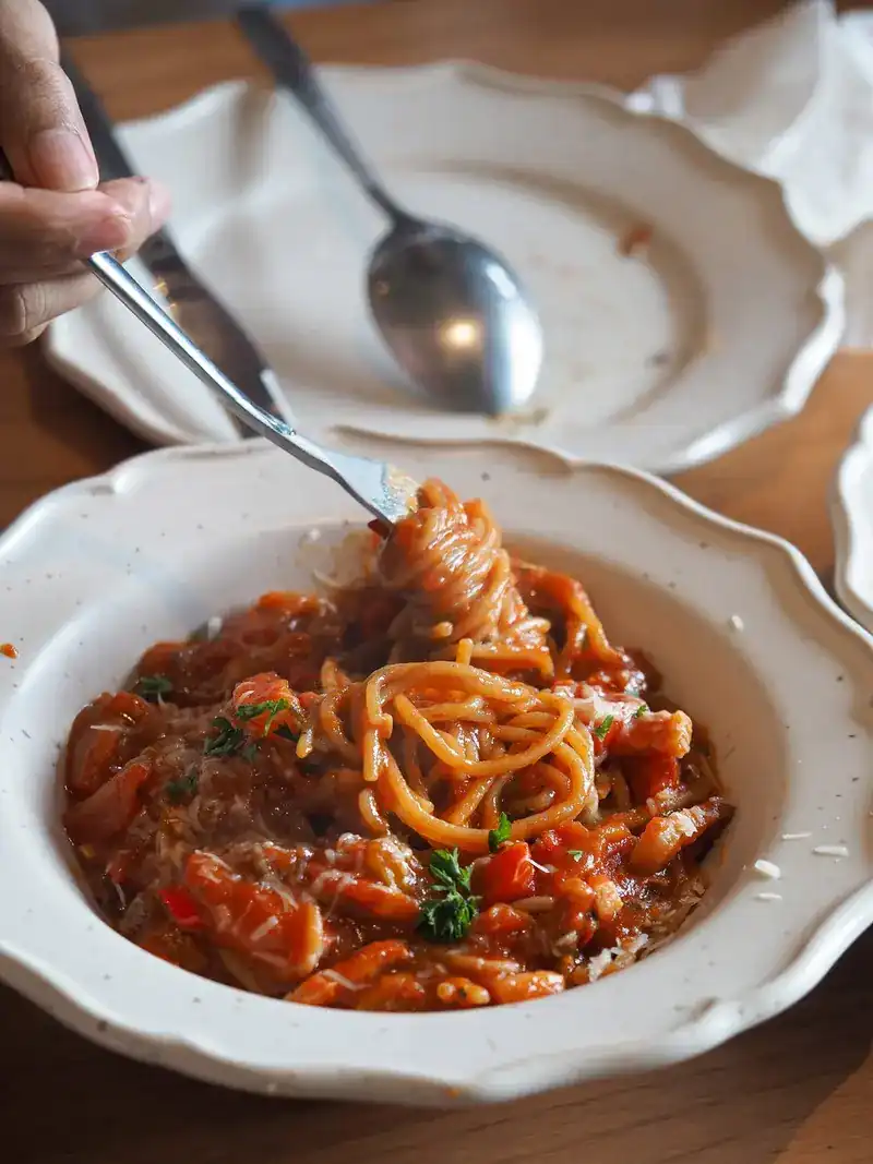 Spaghetti in a red tomato sauce twirled on a fork over a scalloped bowl