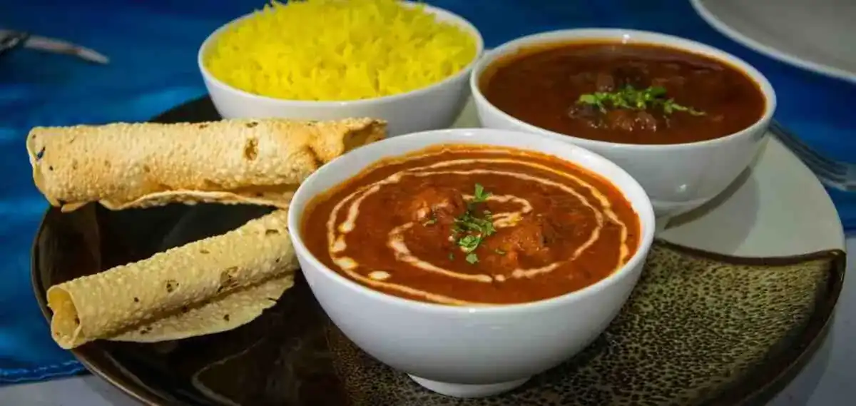Non-veg thali: butter-swirled curry, lamb curry, yellow rice and rolled papadums