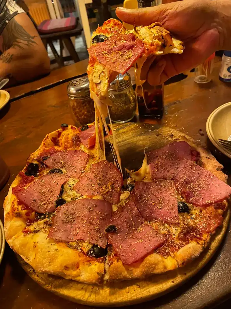 A slice lifted from the pizza, the cheese stretching