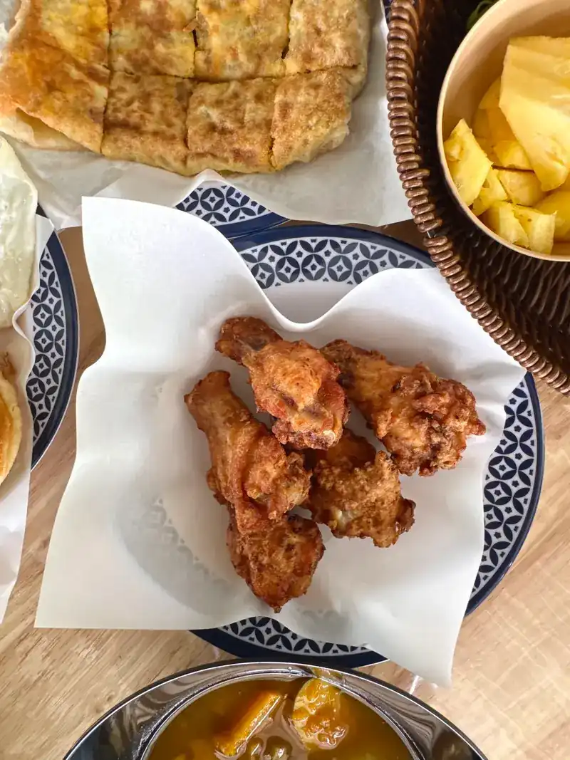 Fried chicken on a blue-and-white plate, with roti and pineapple beside it
