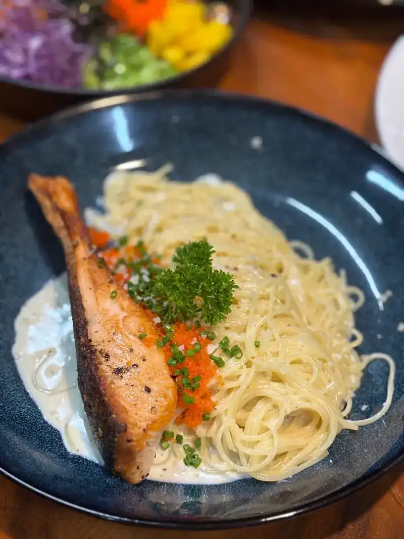 Spaghetti in cream sauce with a piece of grilled salmon