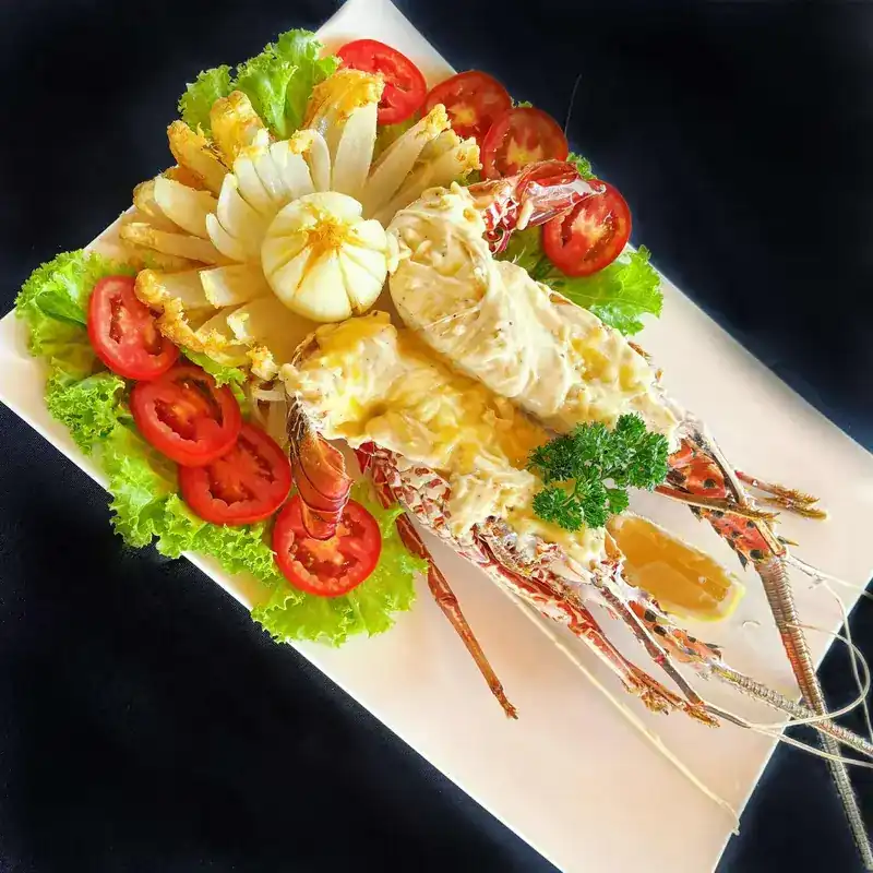 Lobster on a platter with tomato, lettuce and a carved onion