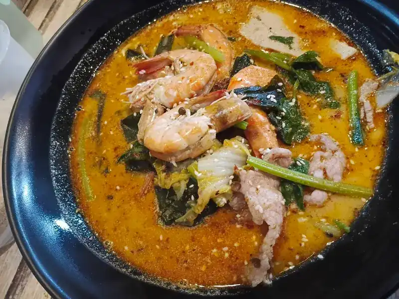 Malatang with prawns, sliced pork, Chinese cabbage and greens in an orange mala broth